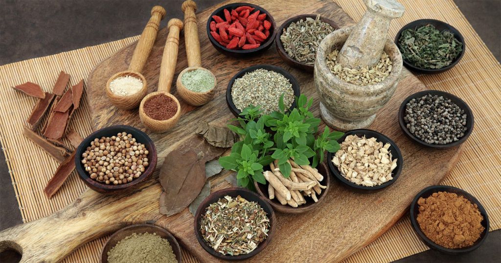 verschiedene Ayurveda Gewürze auf einem großen Holztablett